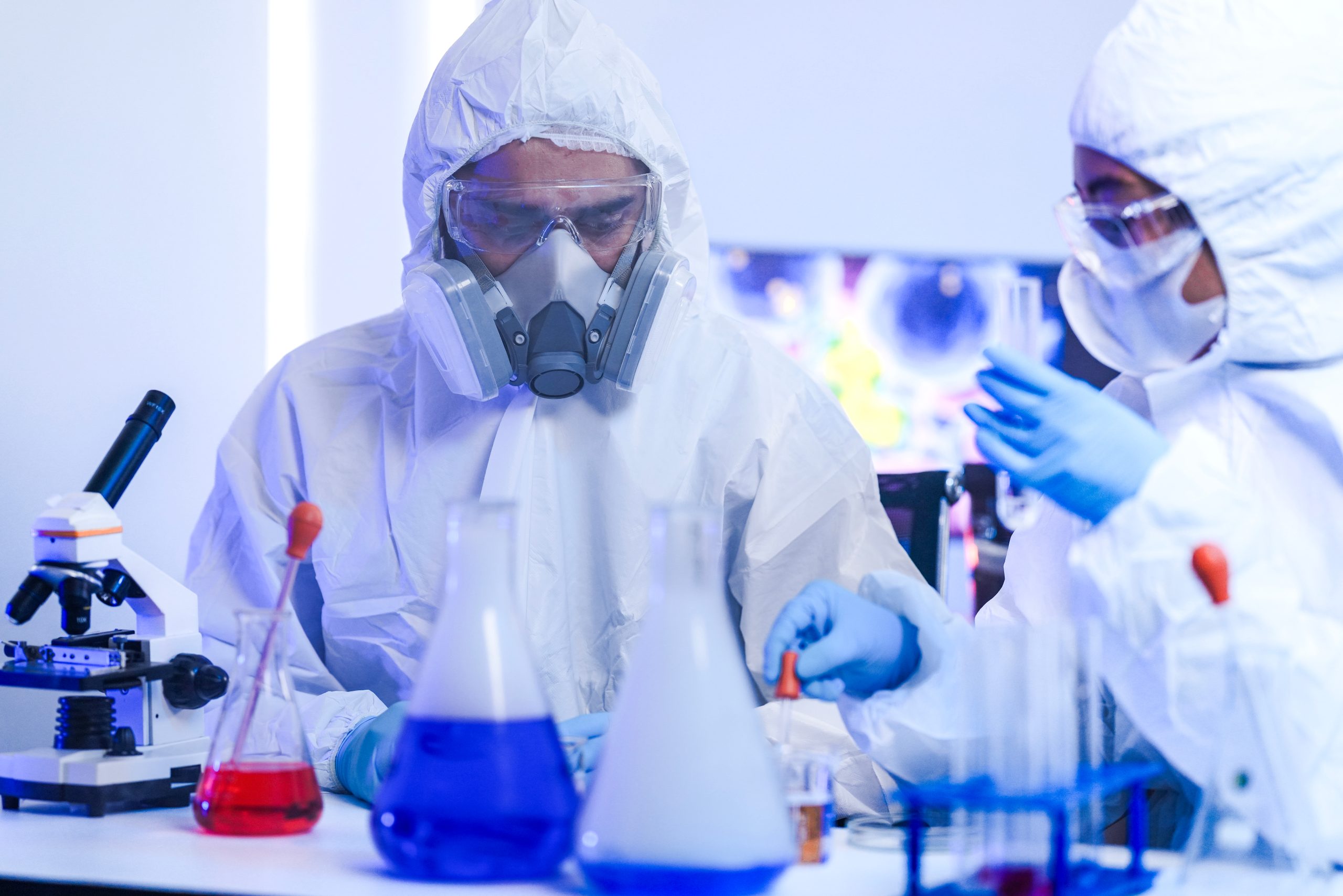 Team scientists in hazmat suits and a respirator conduct research in a high-security lab. They analyze chemical samples while working on virology or vaccine development. Quantitative Fit Testing